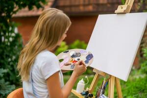 Woman enjoys woman painting on canvas outdoor. photo