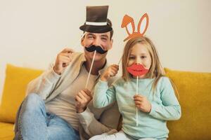 Father and daughter having fun with party props at their home photo