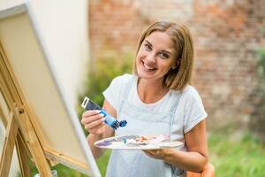 Woman enjoys woman painting on canvas outdoor photo