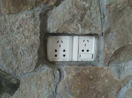 Old white electrical outlet on a stone wall with copy space for text photo