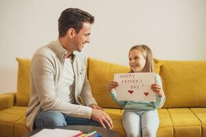 Happy daughter holding greeting card with heart shapes and text for her father.Father's day concept. photo