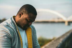 Depressed black man sitting outdoor photo