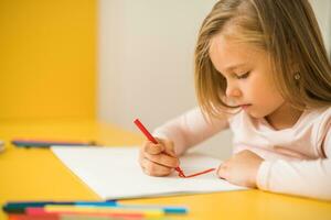 hermosa pequeño niña disfruta dibujo a su hogar foto