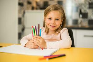 hermosa pequeño niña disfruta dibujo a su hogar foto