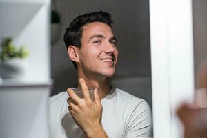 Man using perfume while looking himself in the mirror photo