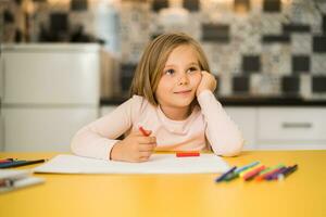 hermosa pequeño niña disfruta dibujo a su hogar foto