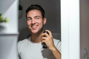 Man using deodorant while looking himself in the mirror photo