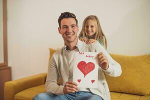 Happy father and daughter holding greeting card with heart shapes and text. Father's day concept. photo