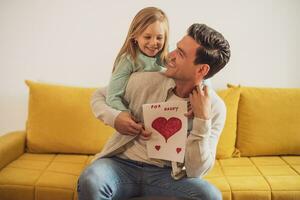 Happy father and daughter holding greeting card with heart shapes and text. Father's day concept. photo