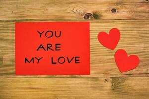 Message you are my love on red paper and hearts on wooden table photo