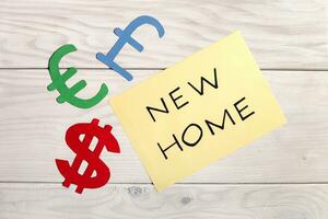 New home concept with euro sign, dollar sign and euro sign on wooden background photo