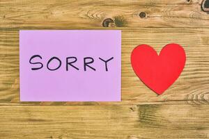 Sorry note on wooden table with heart photo