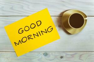 Good morning note on wooden table with cup of coffee photo