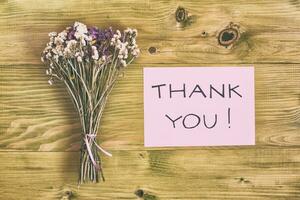 Beautiful bouquet of flowers and text thank you on wooden table photo