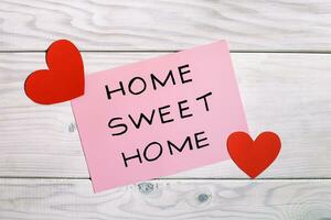 Home sweet home text with hearts on wooden background photo