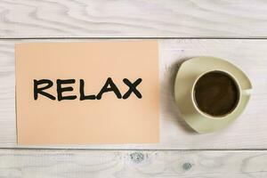 Word relax with cup of coffee on wooden table photo