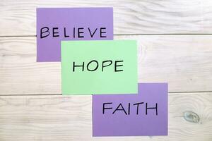 Three different colored post-it notes with the words believe, hope, and faith photo