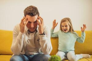 Daughter is screaming at her stressed father at their home. photo