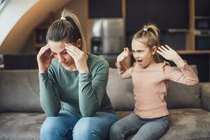 Stressed mother is feeling desperate because of screaming her daughter photo