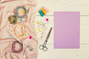 Sewing accessories with empty paper on wooden table photo