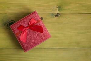 Red gift box with red ribbon on wooden background photo