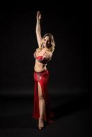 Beautiful belly dancer performing belly dance on black background photo