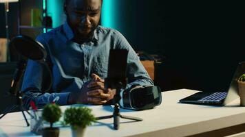 technologie contenu créateur tournage La technologie la revue de nouvellement libéré jeu vr des lunettes pour public dans Accueil studio. bipoc influenceur montrant virtuel réalité casque à les abonnés video