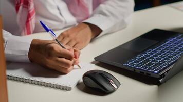 uomo a casa pagare Attenzione nel elearning seminario Teleconferenza con insegnante, scrittura su bloc notes. homeschooling alunno ascoltando per lezione mentre fare il suo compiti a casa compiti video