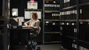 Solving the crime, private detective comes and examines evidence on personal computer. Female police officer with backpack enters workplace and sets laptop on desk to check records and analyse clues. photo