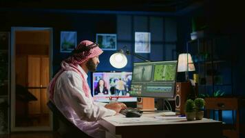 Muslim Kolorist tragen Kopfhörer während Bearbeitung Projekt, Erstellen Film Montage, Arbeiten mit Bilder und Geräusche. Mann mit Video Schneiden Technologie zu Prozess Film auf pc Arbeitsplatz