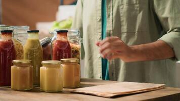 Client filling in paper bag with pasta to buy right amount for healthy meal, pouring natural bio merchandise sold as bulk products in reusable jars. Man going grocery shopping. Handheld shot. video