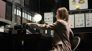 Caucasian criminologist prepares to leave office, packing files and evidence. Female private investigator closing the laptop on workstation after completing research on criminal case investigation. photo