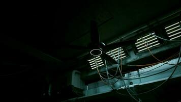 A dark concrete interior with a ceiling fan and multiple wires hanging from it video