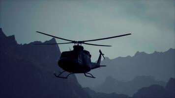 A black helicopter flying over a mountain range video