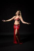 Beautiful belly dancer performing belly dance on black background photo