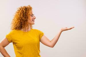 Image of beautiful ginger woman showing palm of hand on gray background. photo