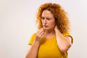 jengibre mujer es teniendo cuello dolor y ella es acerca de a tomar algunos pastillas a ayuda sí misma foto