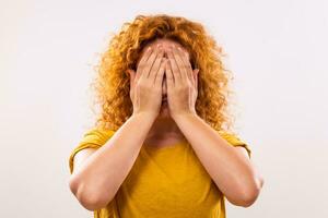 Image of desperate ginger woman covering her face on gray background photo