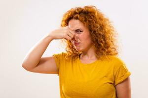 Shocked ginger woman doesn't like how something smells. photo