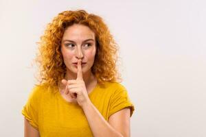 Portrait of a beautiful ginger woman with finger on her lips photo