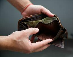 Male hands hold an open wallet and there is only one dollar in it. selective focus photo