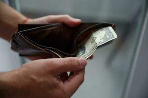 Man's hands pull out a dollar bill from a leather wallet. selective focus photo