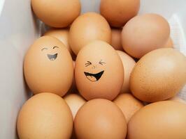 funny laughing chicken eggs in a tray with other eggs. selective focus photo