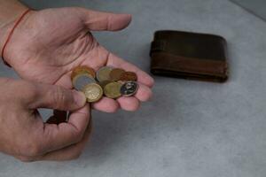 manos de un hombre quien son contando metal monedas en el palma y un cuero billetera .selectivo atención foto