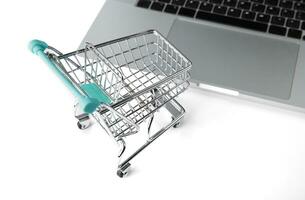 miniature shopping cart from a store stands next to a laptop. selective focus photo