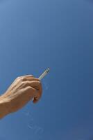 cigarette in man hand against a blue sky. close up. High quality photo