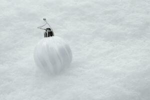 white ball with Christmas tree lies on pure snow. High quality photo