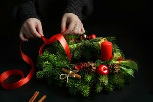 Christmas and holiday concept.cropped image of young woman, hands tying bow on Christmas wreath. selective focus photo