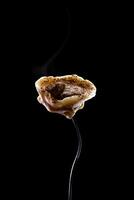 Russian dumpling sprinkled with pepper on fork on the black background . selective focus photo