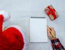 niño escribe letra a Papa Noel y allí es caja con regalo cercano. selectivo atención foto